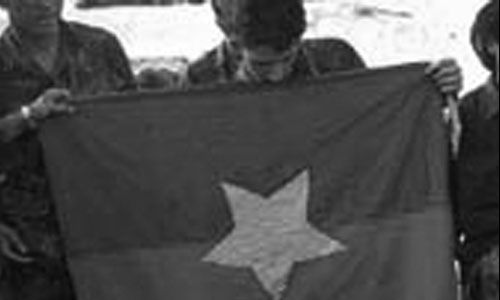 Soldier holding up a flag. 