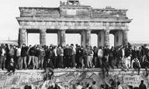 People climbing the Berlin Wall. 